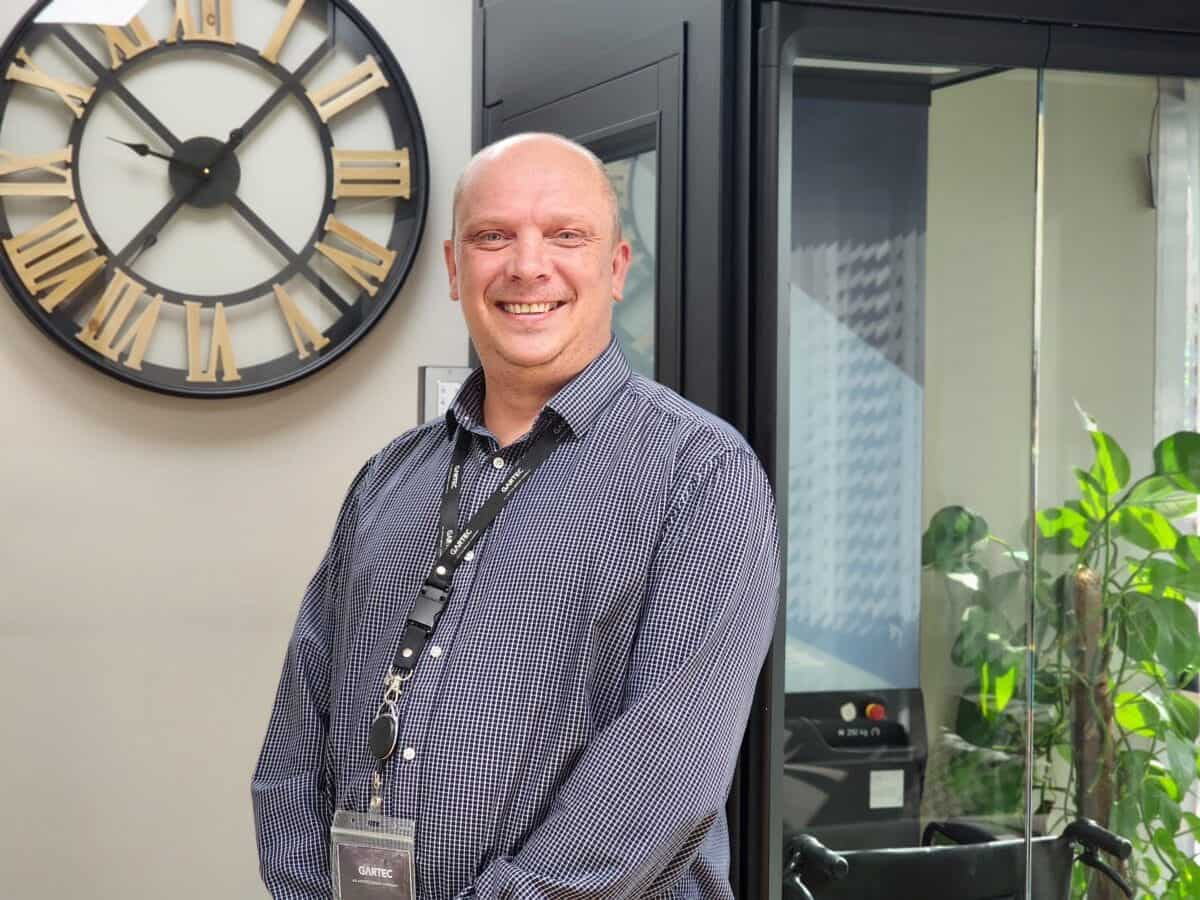 Stuart_Gartec Trade Manager (6) A man standing in front of a clock in a room